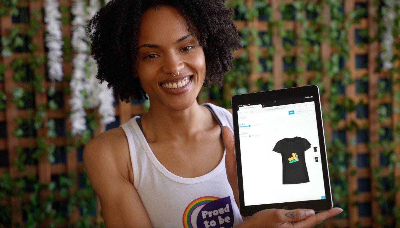 creator holding up a mockup of a design on a t-shirt they created using spreadshop